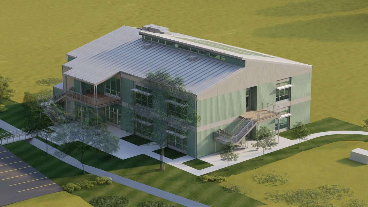 Rendering of a modern, three-story green and gray building with metal roofing, large windows, and multiple staircases, situated in a landscaped area near a parking lot.