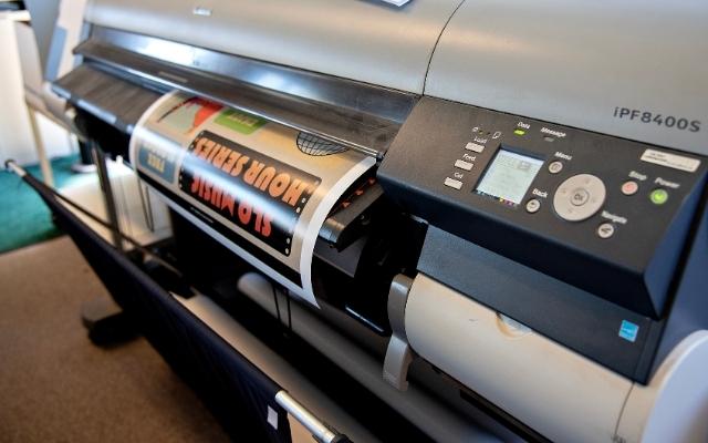 A large-format printer produces a colorful poster at Cal Poly Print and Copy Services.